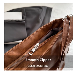 Close-up of smooth metal zipper and matte brown leather detail on a commute tote bag