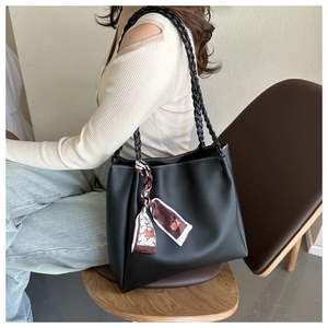 Detail der schwarzen Leder-Tote-Bag mit geflochtenen Riemen und dekorativem Seidenschal