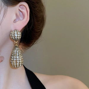 Close-up of sparkling gold drop earrings with rhinestones on model for a vintage look
