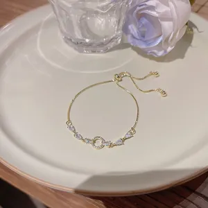 Dettaglio del bracciale dorato regolabile con fiore in zircone e chiusura scorrevole