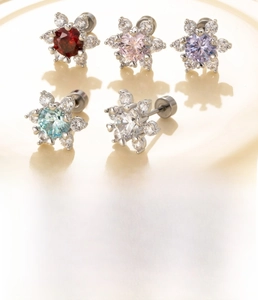 Detail of colorful flower stud earrings set with zircon stones on a white ceramic plate