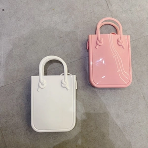 Detailed top view of mini PVC jelly bags in white and pink with knot handle accents