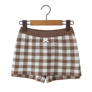 Detailed view of checkered knit shorts with white decorative bow on a wooden hanger
