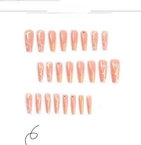 Detail of long orange and nude press-on nails with white flower art and rhinestones