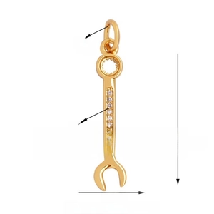 Detailed macro view of a gold-plated wrench pendant with sparkling cubic zirconia stones