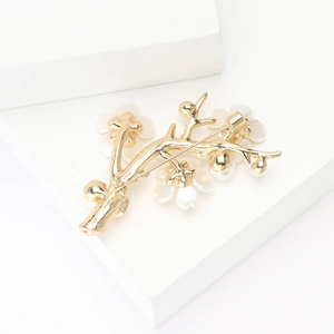 Detailed view of a gold branch brooch with white plum blossoms and elegant pearls