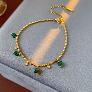 Détail d'un bracelet vintage doré avec breloques cœur en malachite verte sur velours