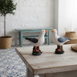 Pair of Nordic resin seagull statues on wooden table with Mediterranean decor style