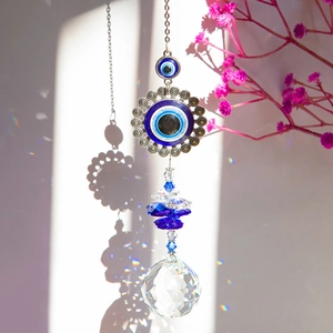 Macro view of crystal suncatcher ball and blue evil eye amulet casting rainbow light