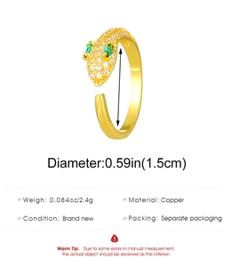 Detailed view of gold copper snake ring with white zircon paving and green gem eyes
