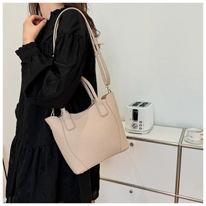 Détail d'un sac seau blanc crème avec grain de litchi, bandoulière et boucles dorées