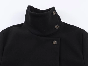 Detail of stand collar and marble textured button on a black short coat with clean white background