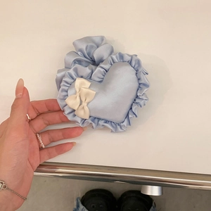 Detailansicht eines hellblauen herzförmigen Haargummis mit Rüschen und Schleife