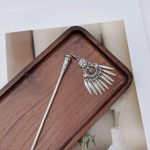 Detail of silver ethnic hair stick with blue beads and leaf tassels on wooden tray