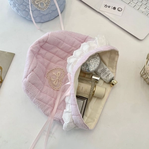 Detail of pink striped quilted fabric storage bag with heart lace and bow embroidery