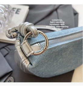 Macro shot of silver metal hook and light blue denim material on luxury saddle bag