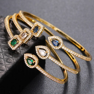 Macro shot of gold brass bangles with green, blue, and white zircon gemstones