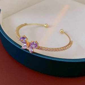 Détail du bracelet doré avec papillon en zircon violet dans son coffret de luxe