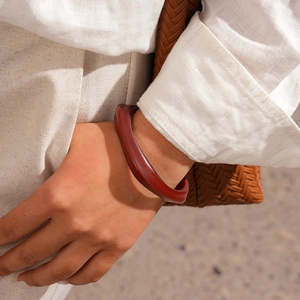Close-up of a reddish-brown acrylic geometric bangle worn with bohemian linen attire