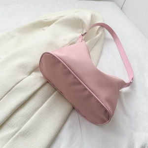 Sac à épaule minimaliste rose en nylon posé sur un tissu texturé pour femmes