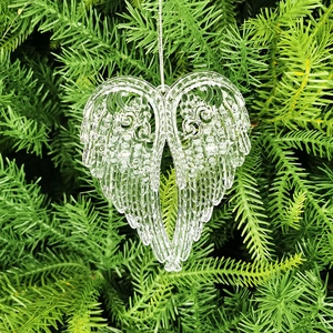 Clear acrylic heart-shaped angel wings ornament hanging on a Christmas tree branch