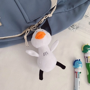 Close-up of a cute white plush duck charm with orange beak on a blue backpack strap