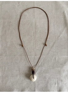 Détail d'un collier de style ethnique avec pendentif anneau bodhi sur cordon marron