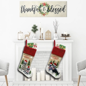 Knitted Christmas stockings with dog and tree patterns hanging on a decorated fireplace