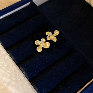 Boucles d'oreilles fleurs dorées minimalistes avec texture pétale sur boîte en velours