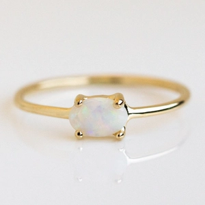 Close-up of minimalist 18k gold plated ring featuring an oval white opal in 4-prong setting