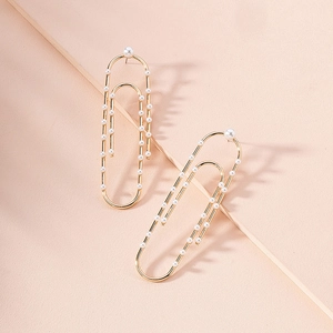 Detail view of gold paperclip drop earrings with elegant white pearl accents
