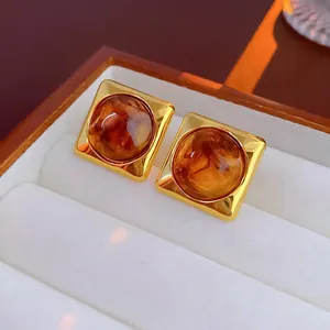 Macro view of vintage gold geometric earrings with amber tiger eye stones in jewelry box
