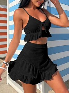 Détail du tissu brodé noir avec volants et nœud sur un ensemble de bikini trois pièces