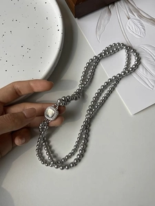 Detailed close-up of double-layer grey pearl necklace with square mother of pearl clasp