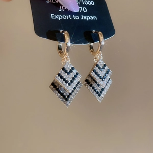 Détails des boucles d'oreilles losange avec zircons bleus et blancs sur monture dorée