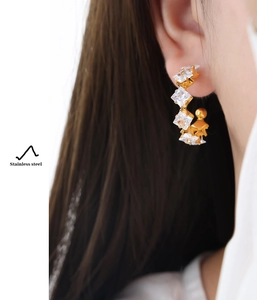 Detailed close-up of C-shaped 18K gold plated stainless steel earring with square zircons
