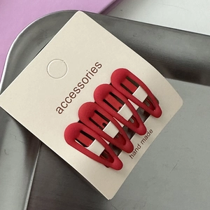 Close-up of four red matte star hair clips set on a handmade display card for girls