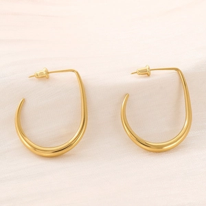 Detailed view of gold U-shaped curved earrings with a sleek polished finish on fabric