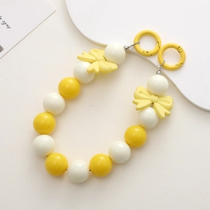 Detail view of 16mm yellow and white acrylic candy beads phone strap with bow charms