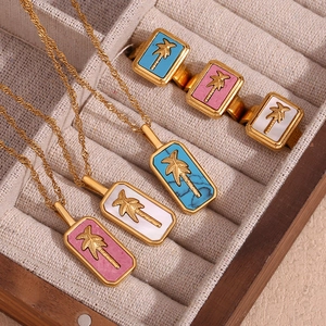Detailed close-up of 18K gold plated rectangular pendant with palm tree on velvet tray