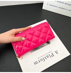 Macro shot of rose red quilted patent leather long wallet with golden zipper detail