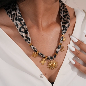 Close-up of leopard print fabric necklace featuring golden sun and butterfly charms