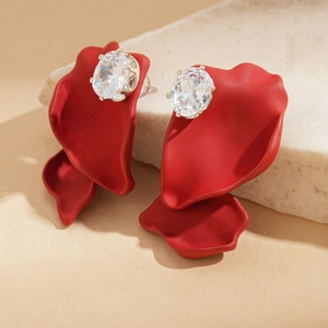 Macro view of matte red petal earrings with a large oval crystal on a stone pedestal