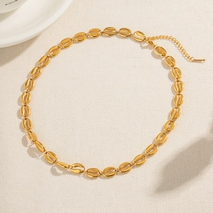 Detailed view of gold stainless steel shell link necklace on beige linen background