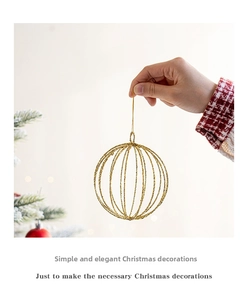 Detail of golden hollow glitter Christmas ball ornament held against a tree