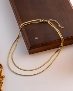 Close-up of golden double-layer necklace with flat snake and twisted rope chains