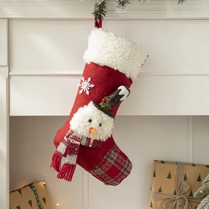 Christmas stocking with snowman decor, red plaid pattern hanging on a white fireplace