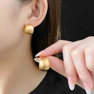 Matte gold-plated hemispherical stud earrings featuring a minimalist brushed metal finish