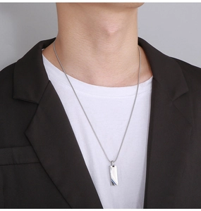 Close-up of polished silver rectangular pendant with a thin snake chain on a male model