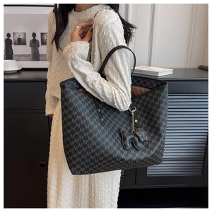 Detail of grey tote bag with M-pattern print, plush charm and spacious brown lining